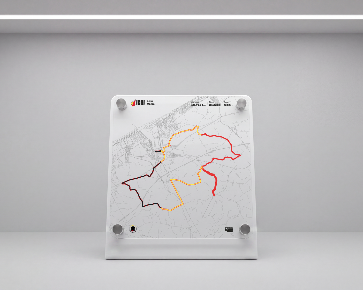 A vertical white map display board mounted on a wall in a minimalist white room, featuring a faint street map with three colored route lines in red, orange, and dark brown.